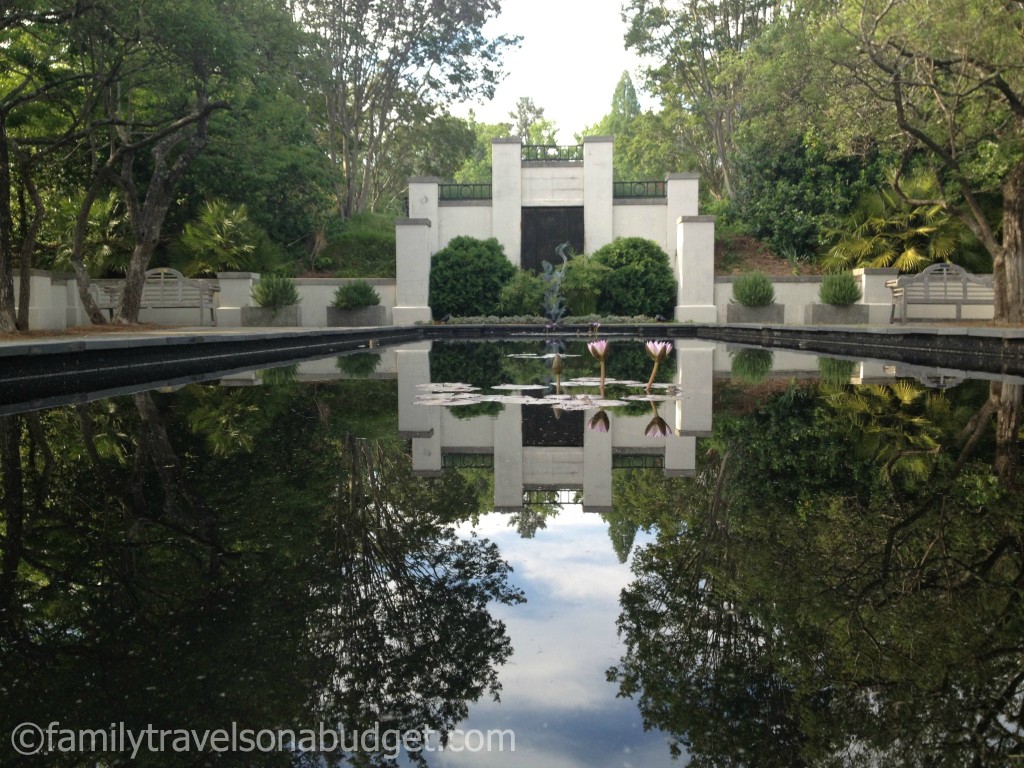 Reflecting pool at Birmingham Botanical Gardens with park benches on either side.