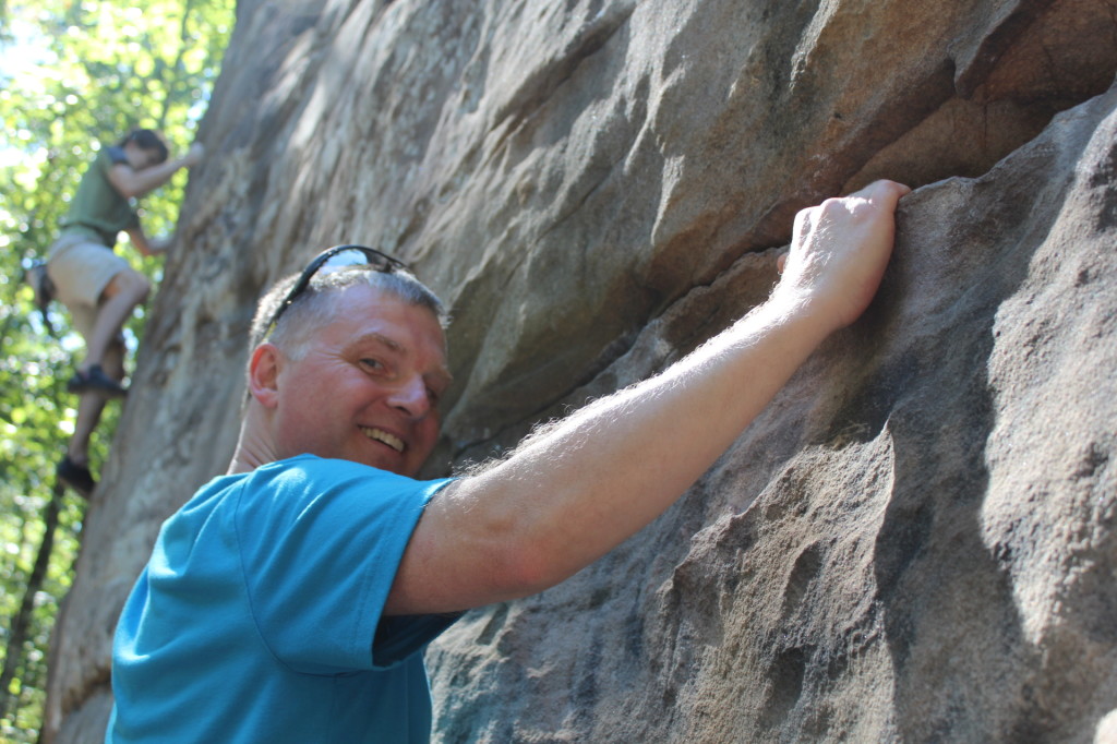 Rock climbing at Moss Rock Preserve, Alabama -- man in foreground smiling and teen in background in climbing gear