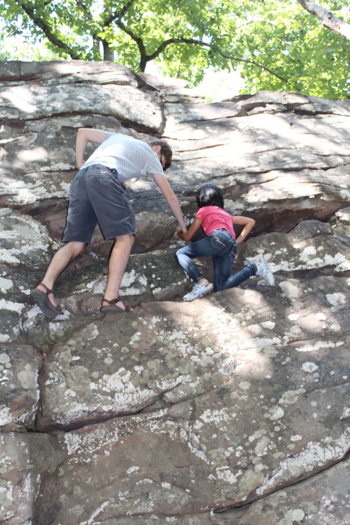 Young adult helping a child climb one of the easier bouldering routes at Moss Rock Preserve