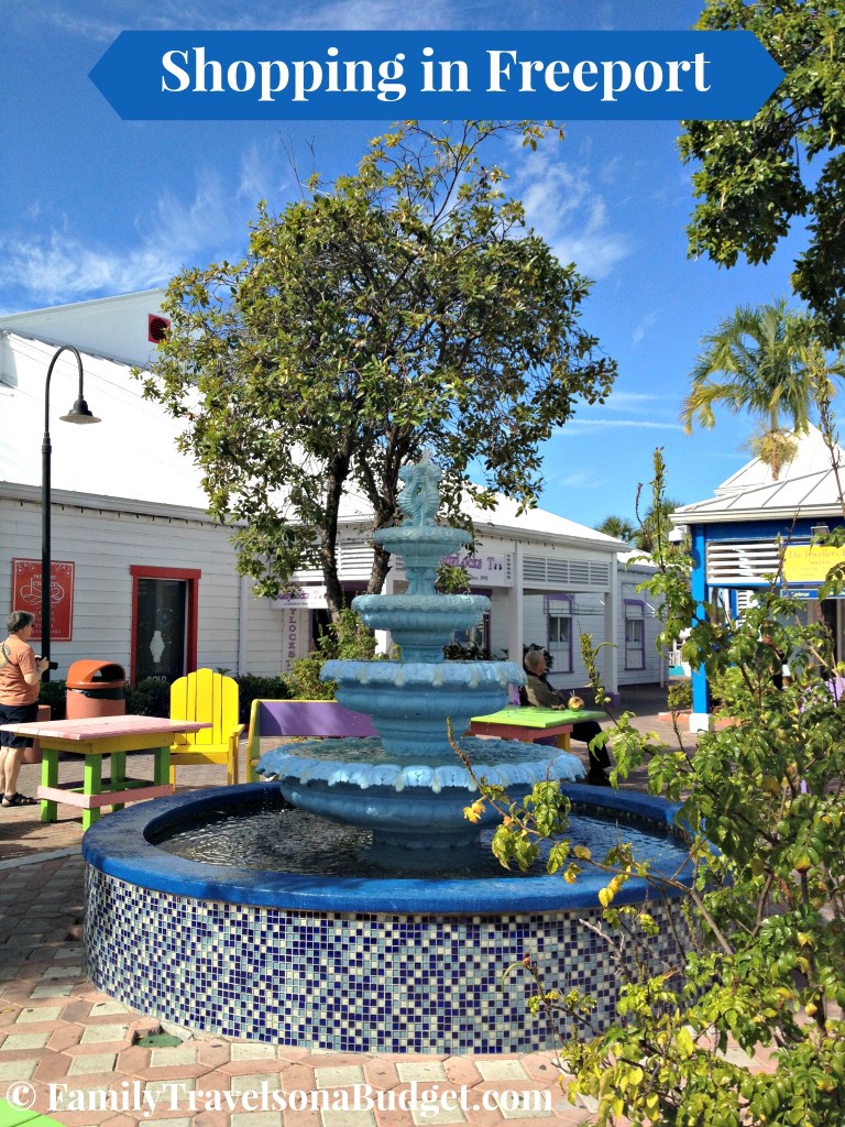 Shopping area in Freeport, the Bahamas with a water fountain and outdoor dining tables.