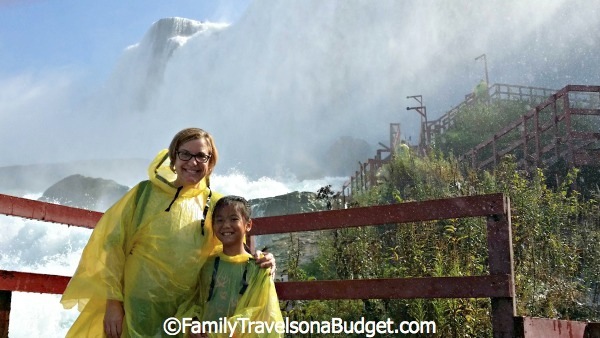 Mother and daughter in yellow ponchos at Cave of the Winds with wooden stairs and walkway behind