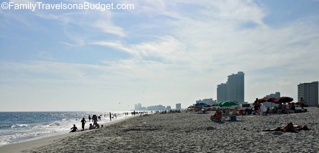 Wide sandy beach with people sunbathing and high rise hotels behind