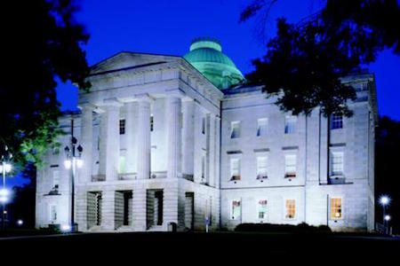 North Carolina Capitol Building at night. White stone with a green dome on top.