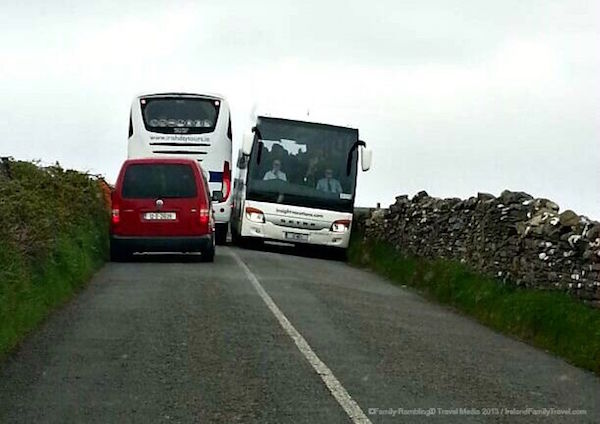 Tour buses near the Cliffs of Moher with a red car behind them