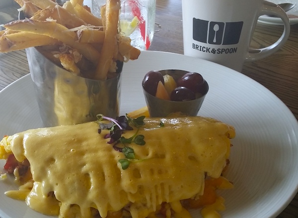 Omelet with fries and fruit cup.