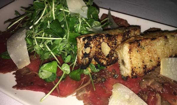 Ostrich carpaccio with toast and greens.