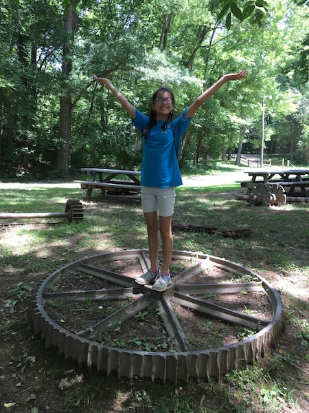 Picnic area at West Point on the Eno. Young girl poses on a historic mill piece.