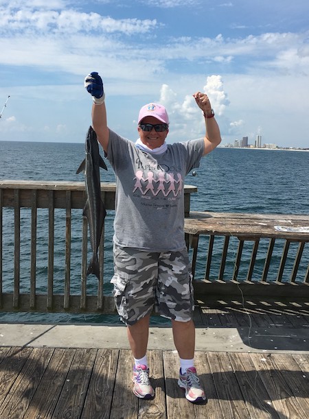 Lady from Arkansas catches her first fish ever at Gulf State Park Pier and displays it proudly.
