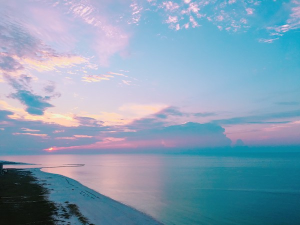 the sky is vivid blue and pink as the sun rises over the Gulf of Mexico