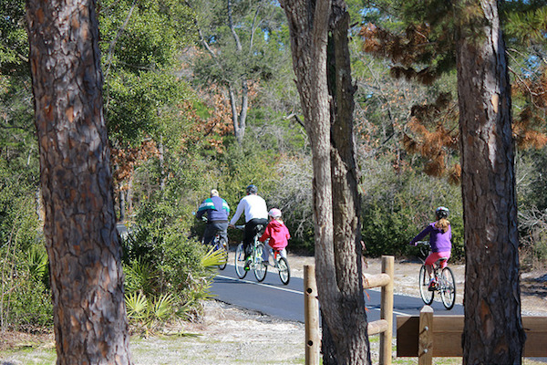 family biking on trail at Gulf State Park: One of the best family campgrounds in the US