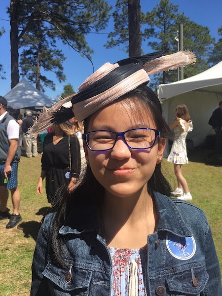 Teen posing in a fascinator for sale at the race track popup shops.