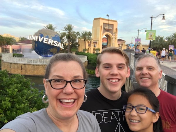 family smiling in front of entrance to Universal Orlando theme park
