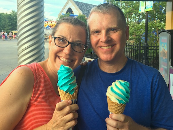 Man in blue shirt and woman in red shirt enjoying blue ice cream in waffle cones at Kings Island