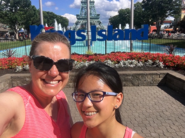 Mother and daughter at entrance to International Street at Kings Island, with Eiffel Tower and blue fountains in background