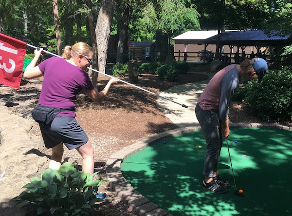 Family fun as a mom pretends to bop her son while he lines up his putt.