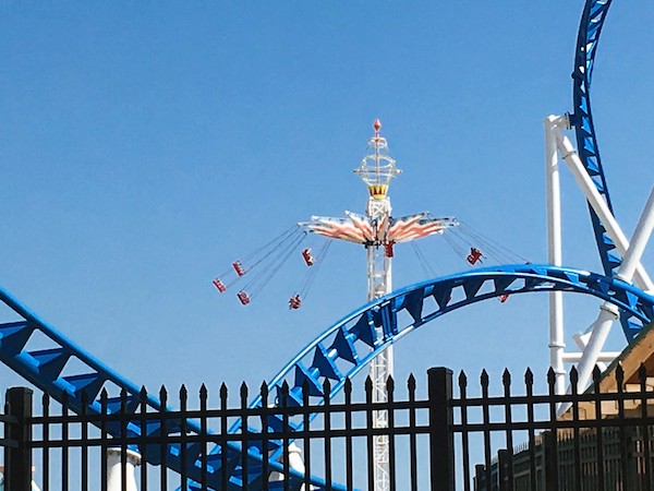 Swings in background with roller coaster in foreground at an amusement park