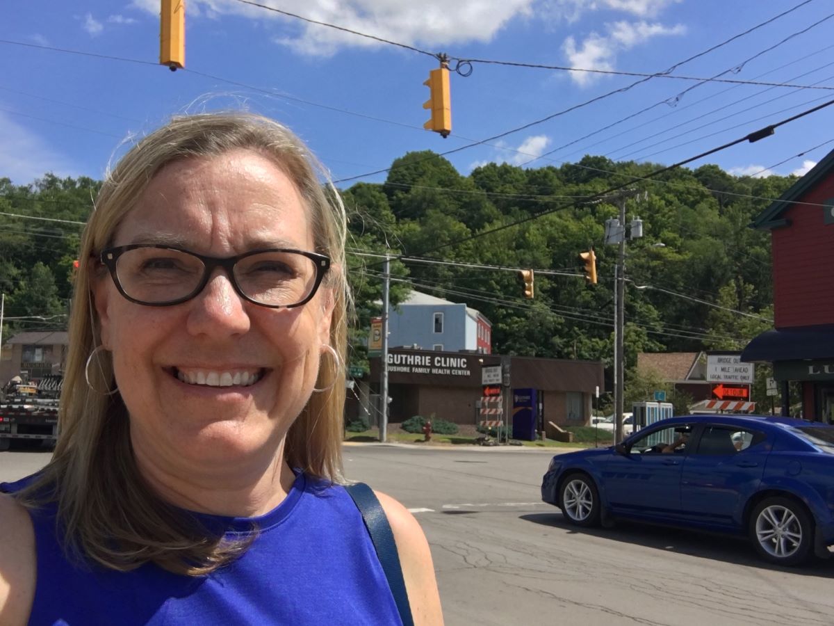 Smiling selfie at the Traffic Light in Dushore Pennsylvania with blue car at the intersection.
