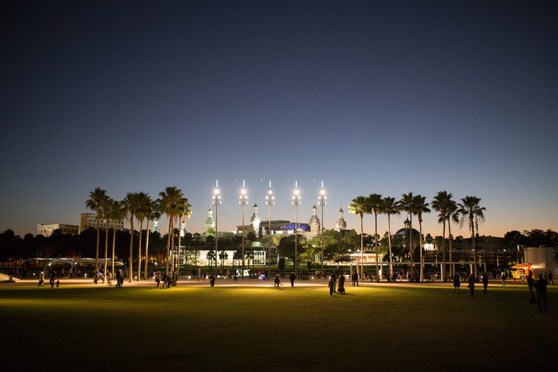 Night scene in Tampa Florida with palm trees, lights and people in a park.