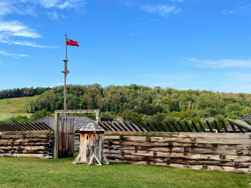 Fort Ligonier, timber fort with British flag and mountains of the Laurel Highlands behind