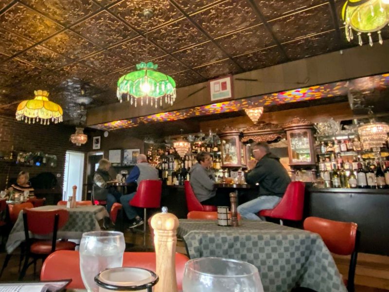 Interior of Sneaky Pete's Modern Speakeasy, one of Erie's best restaurants. Shows bar, tables, lighting and tin ceiling