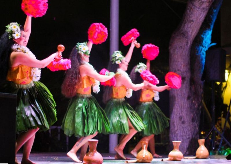 Hula dancers in green skirts at a Hawaiian luau in Oahu
