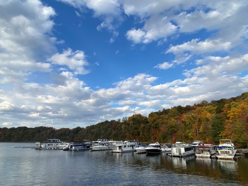 Boats at Lake Raystown Marina with the trees along the shore, and bright blue sky with puffy clouds above