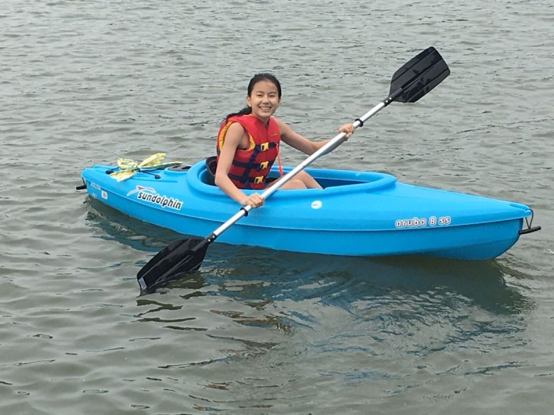 Young girl kayaking in a sundolphin kayak while wearing a red life jacket