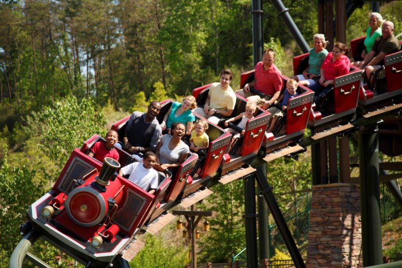 Visiting Dollywood Resort's family friendly roller coaster like the Firechaser. Showing Red train roller coaster with kids and adults smiling