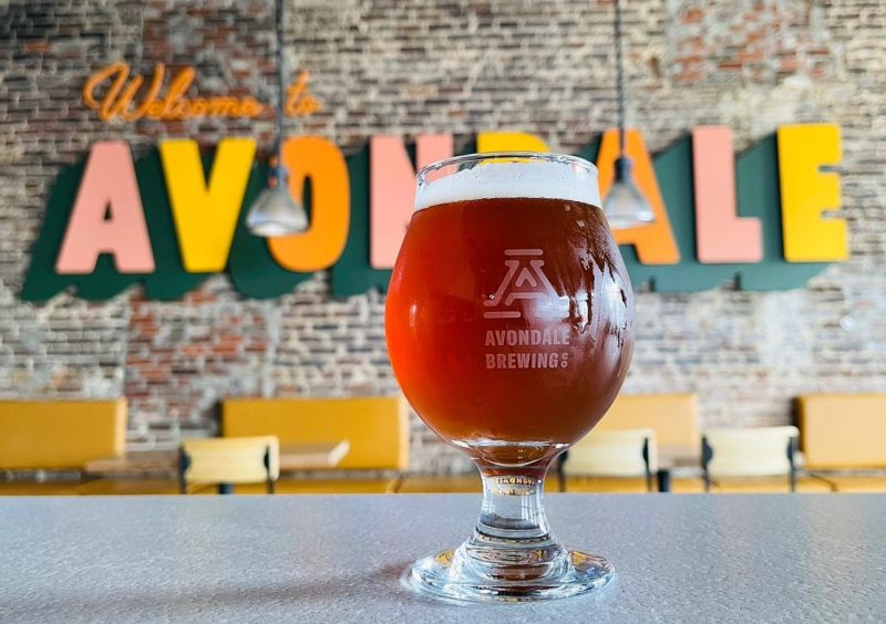 Beer in glass in front of Welcome to Avondale sign at Avondale Brewing in Birmingham, AL