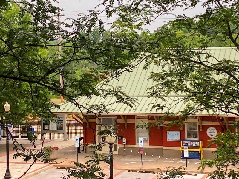 Culpeper, VA train station, red with a metal roof, piano out front, trees, edison lights and a pretty decorative fence