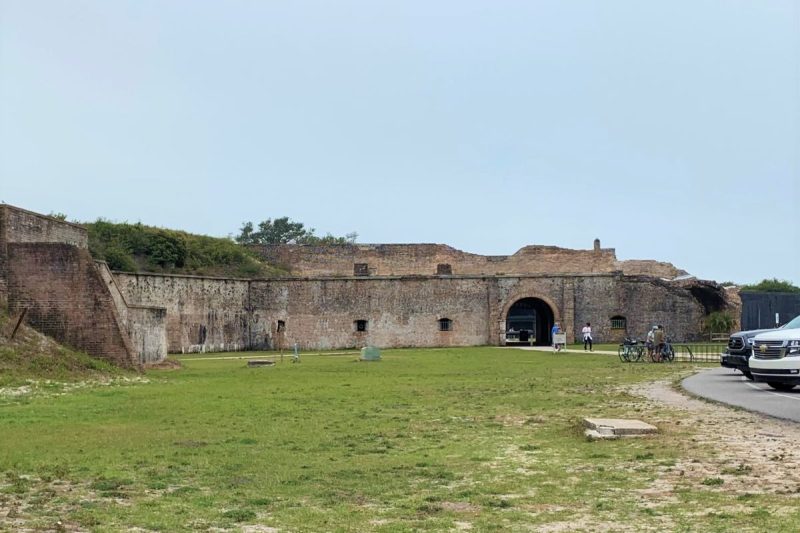 Fort Pickens near Pensacola is an easy walk from Fort Pickens Campground. Image shows peole at the fort entrance, as well as bike rack and parking area.