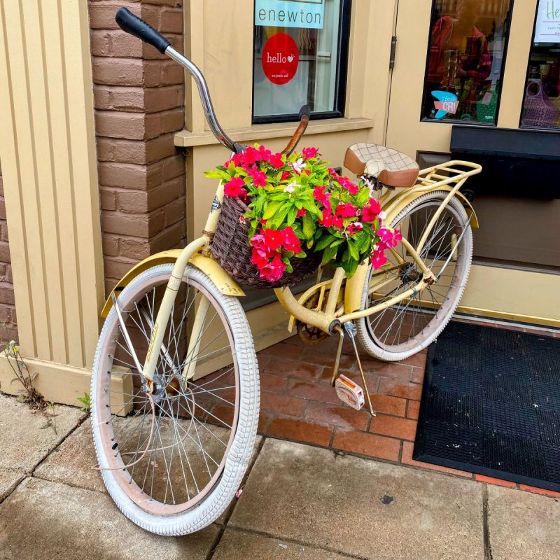 Yellow bike with white tires and a basket filled with flowers outside a shop in Culpeper, Virginia