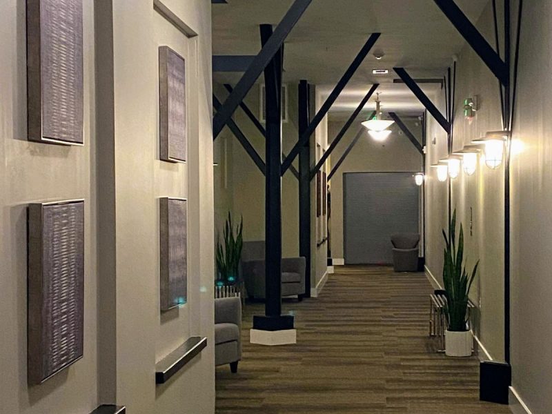 Wood beams and lights in a spacious hallway with plants and seating area at Culpeper Center
