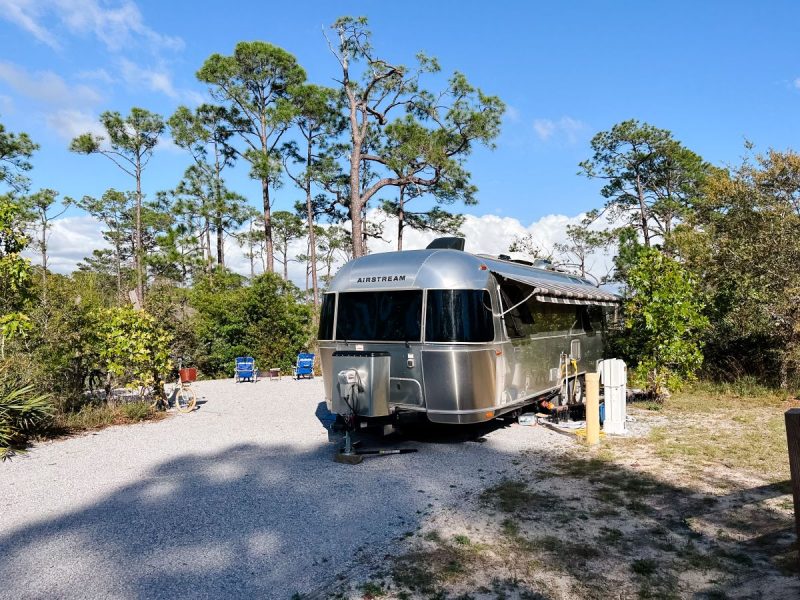 Airstream camper  at a camping site in Henderson Beach Campground near Destin, Florida Pine trees and sand in photo