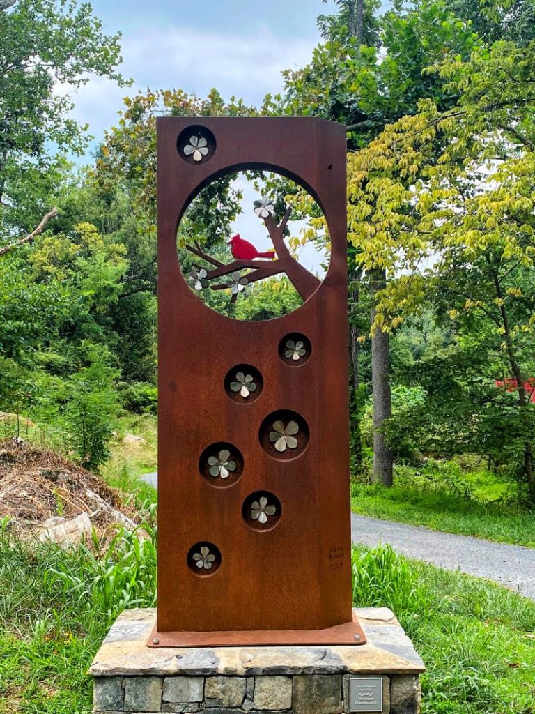 Metal sculpture with cherry blossoms and a red bird along the trails at the MSV