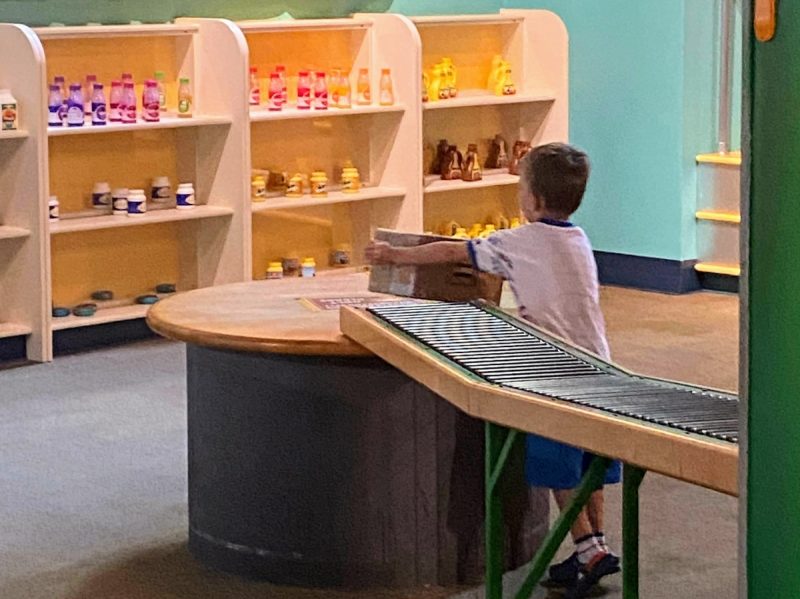 Young boy playing in the Fundamentally Food exhibit at the Children's Museum of Atlanta, unloading a box from the delivery truck