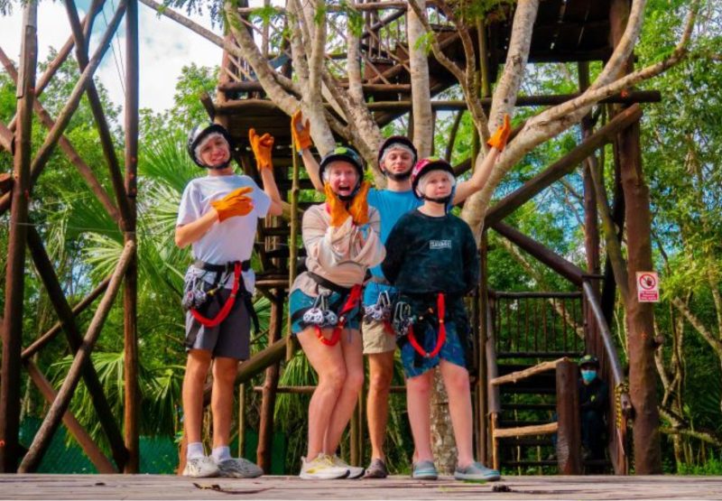 People standing on a ziplining platform with helmets and gloves