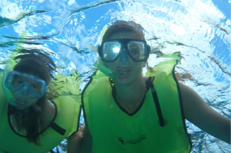 kids in snorkel gear under the water on one of the Cozumel shore excursions