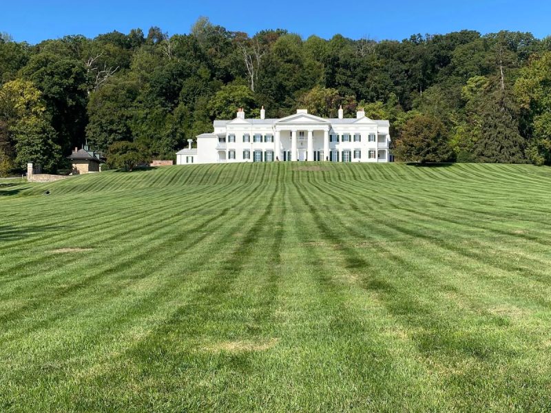 White mansion at Morven Park overlooking the manicured grounds where equestrian events are held, with trees and blue sky in the background. The grounds are open daily and free to the public