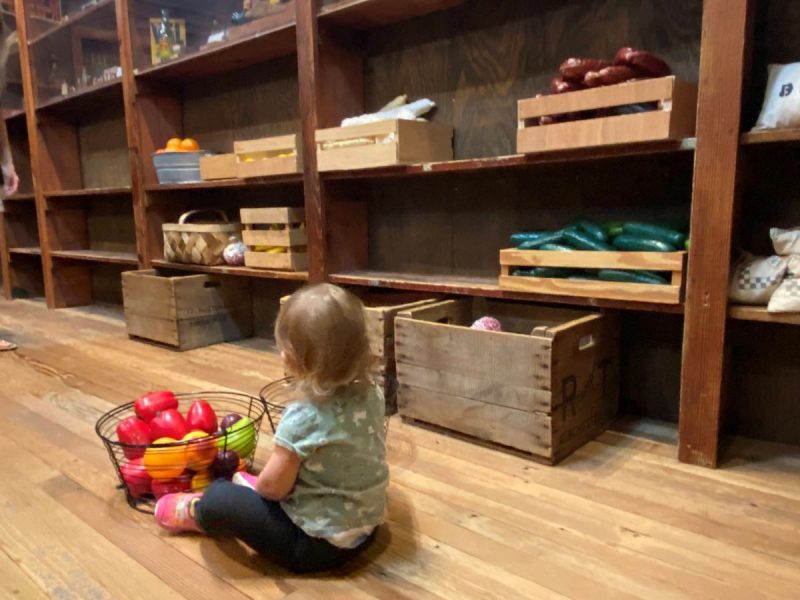 Young child playing with toy vegetables at the Waxpool General Store exhibit at the Loudoun Heritage Farm Museum
