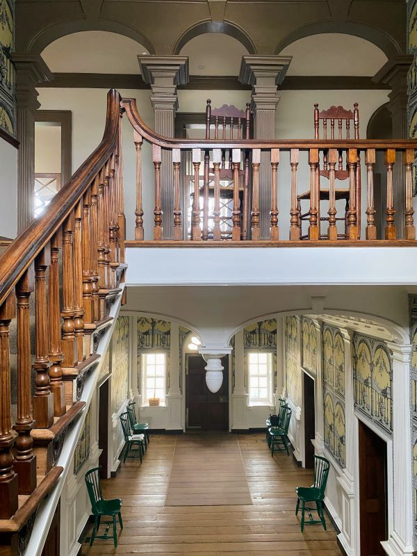 Wooden stairway, elaborate pillars, woodwork and wallpaper interior of Gunston Hall in Fairfax County, VA.