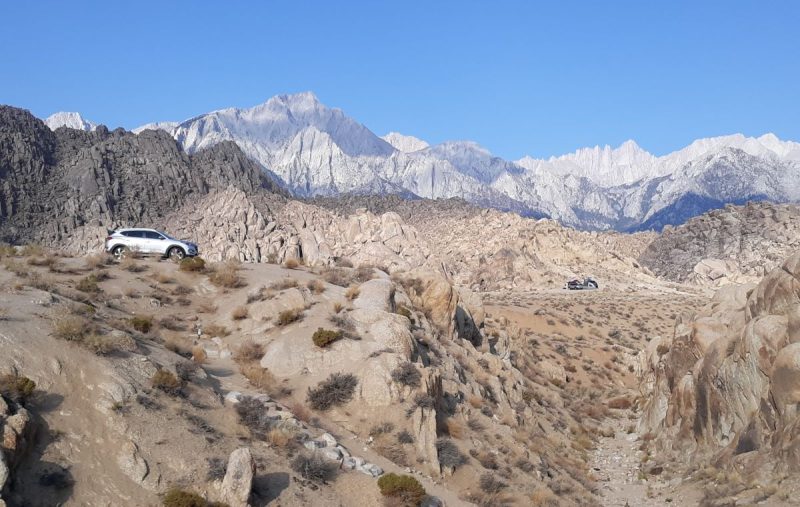 Remote camping in the California mountains showing a car, a campsite and rugged mountains in the background of a desert landscape
