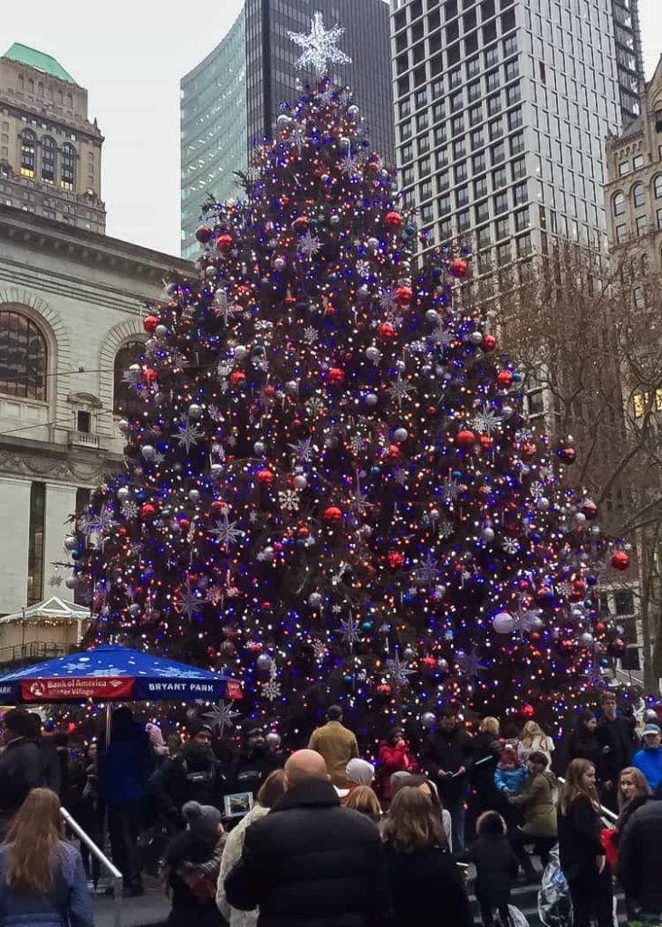 Christmas tree in New York City at Bryant Park Winter Holiday Markets with skyscrapers in background