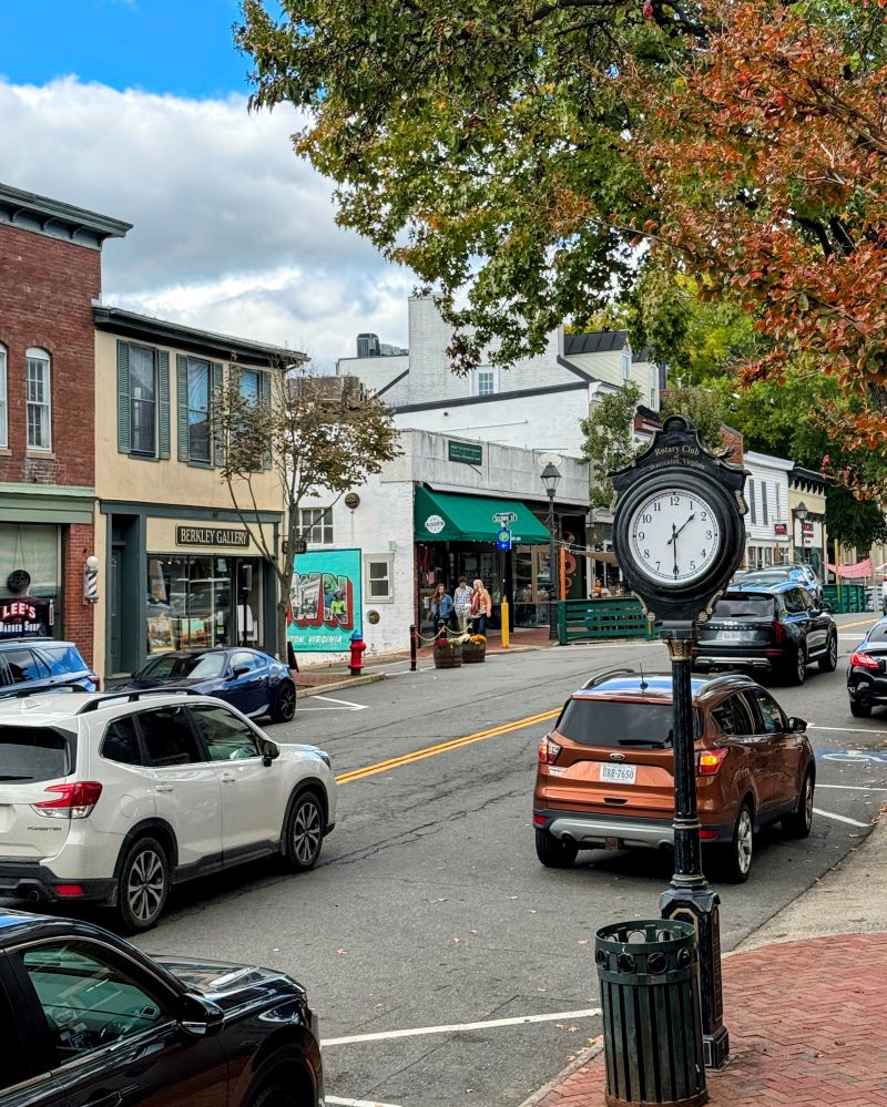 Things to do in Warrenton, VA include shopping the historic Old Town city center. Pictured here are street clocks, shops, people walkking and fall foliage