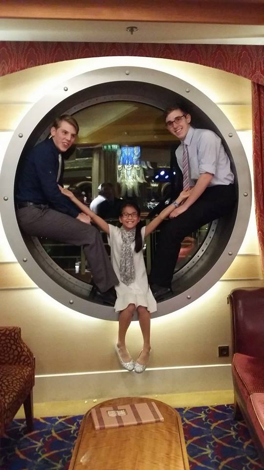 Kids dressed for formal night on the Disney Dream and posing in the porthole window.