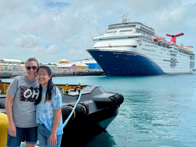Carnival Elation in port in Nassau Bahamas with two ladies posing in front.