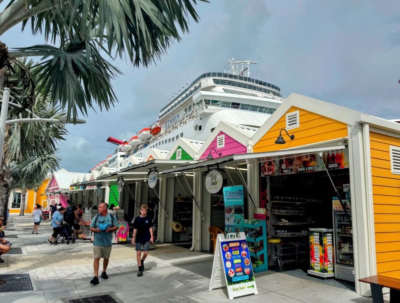 Port Marketplace in Nassau with Carnival Elation in the background and palm trees offering shade.