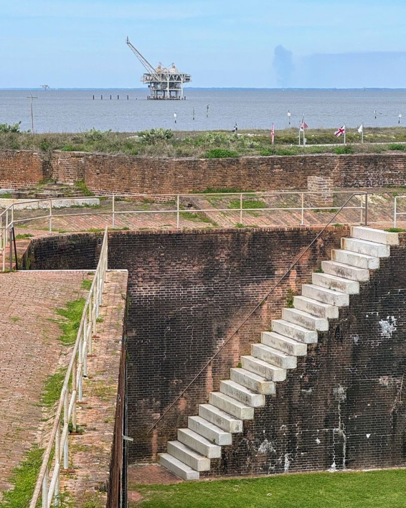 Steep stairs at Fort Morgan with oil drilling platforms in the Gulf of Mexico.