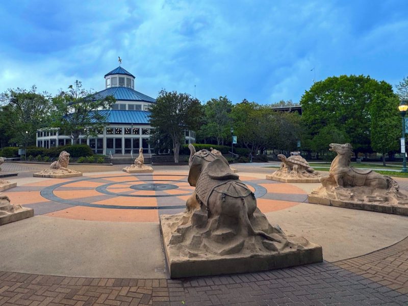 Fountain playground at Coolidge Park in foreground with indoor carousel in background