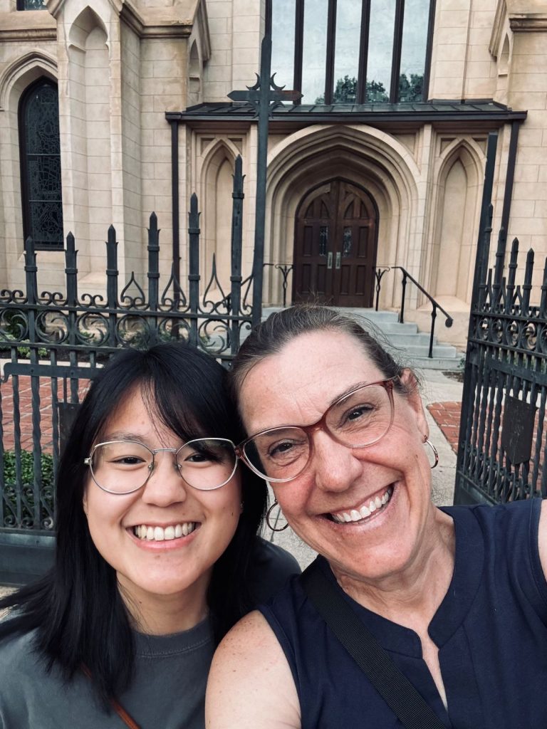 Two women smiling in front of Trinity Episcopal Cathedral.